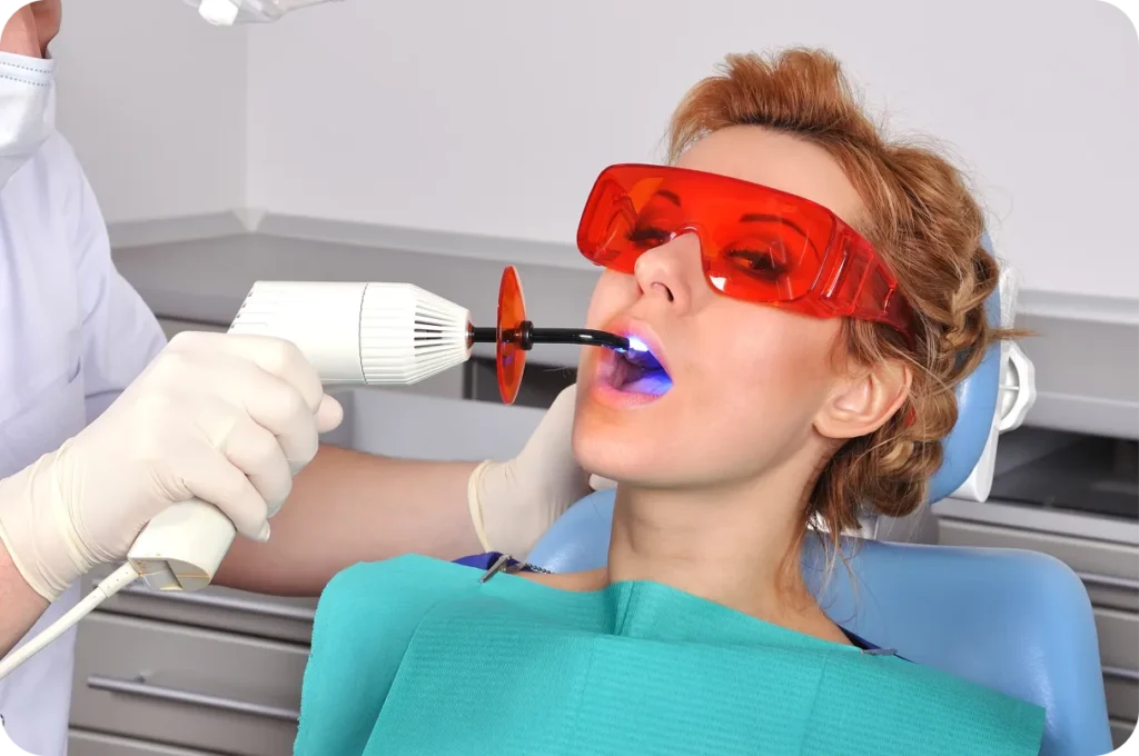A dentist using a curing light on a patient's tooth during a restorative procedure, highlighting the benefits of improved oral function and aesthetics.