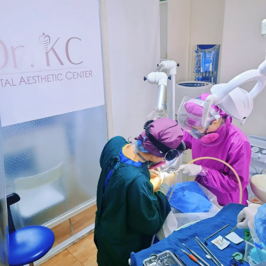 Doctor KC with her assistant during the enamel reshaping service on a patient in a clinic setting.